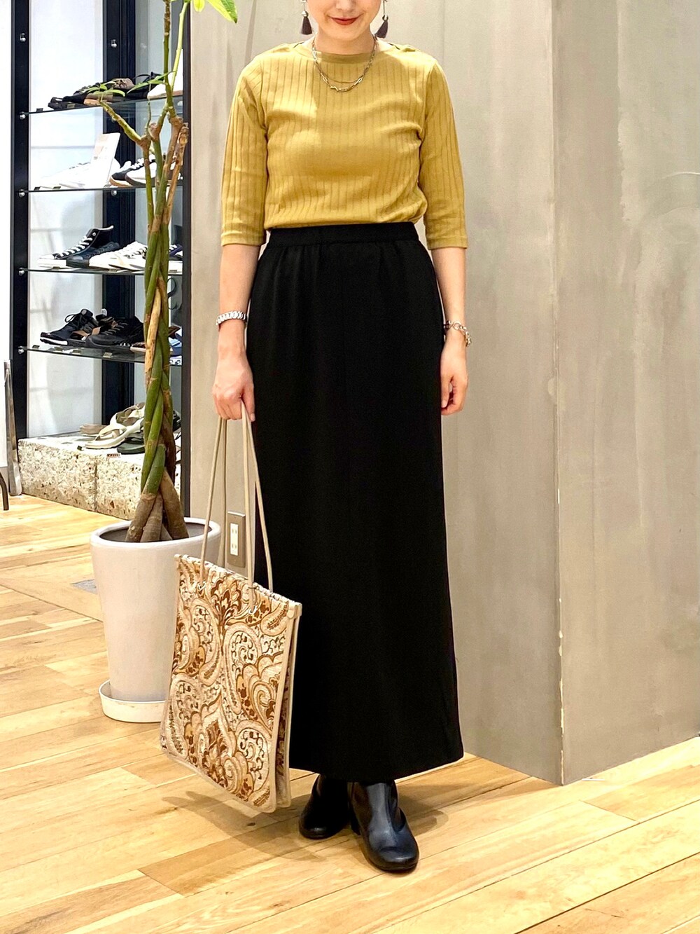 イエロー系のTシャツ/カットソー、ブラック系のスカート、ホワイト系のトートバッグを着用したレディースの秋コーディネートの4枚目の写真