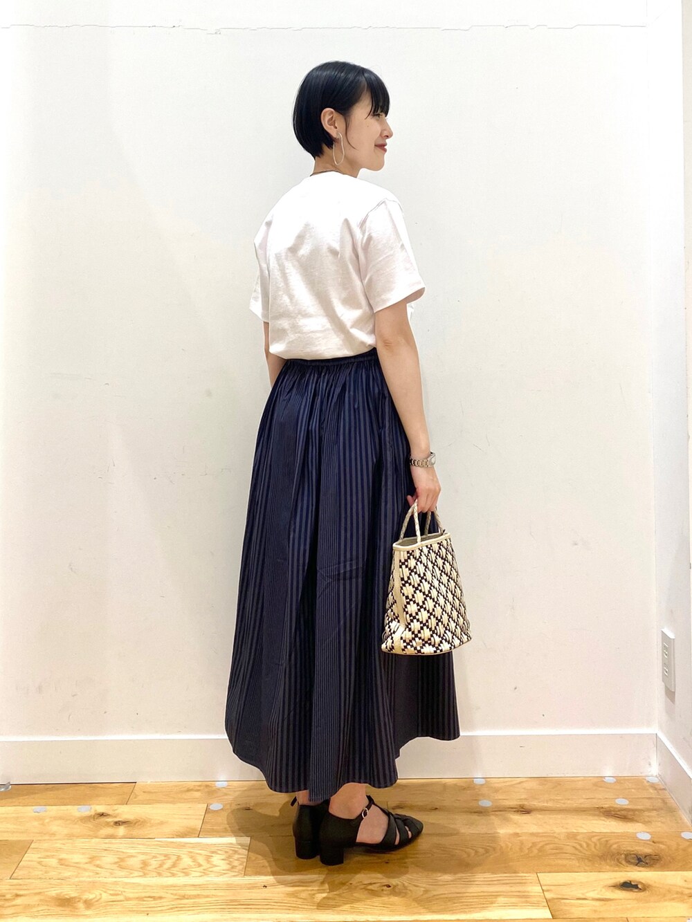 グレー系のスカート、ブラック系のサンダル、ホワイト系のその他を着用したレディースの春コーディネートの3枚目の写真