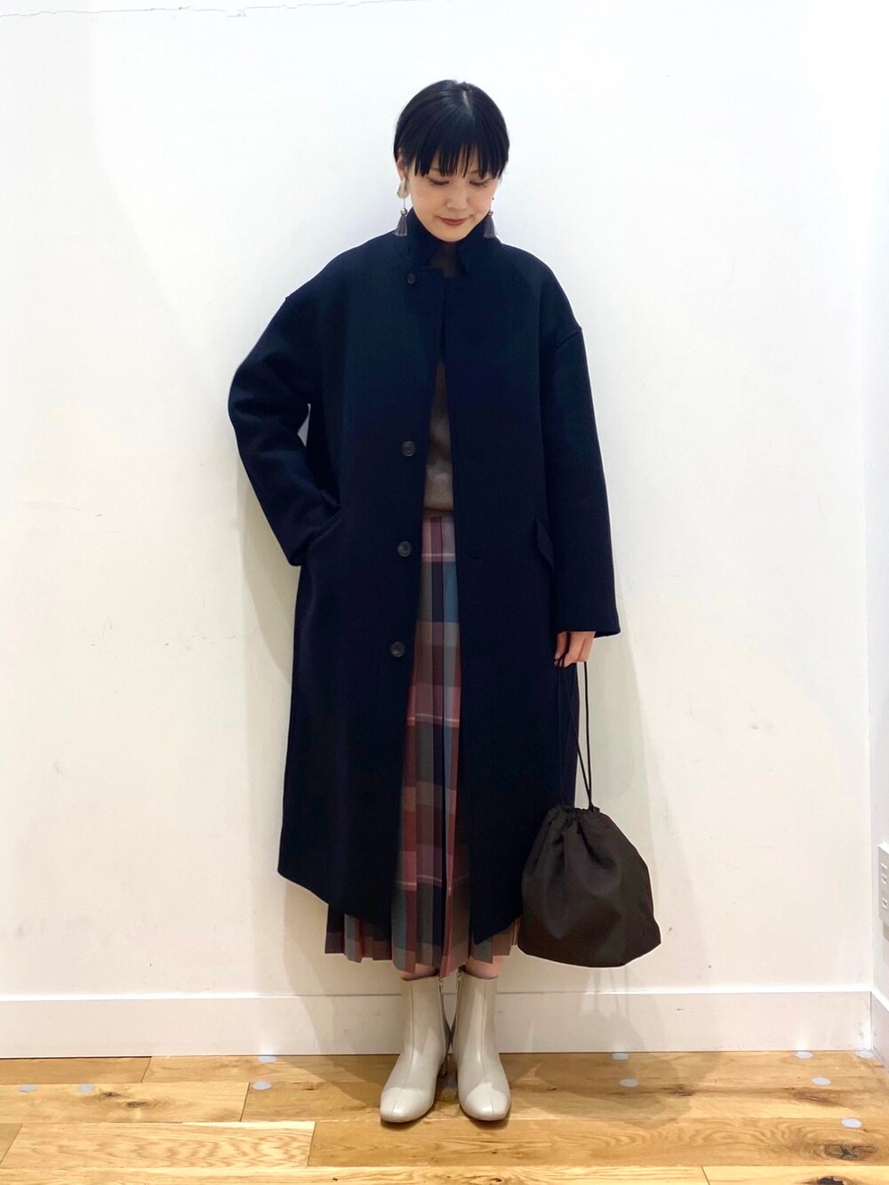 ブルー系のチェスターコート、ブラウン系のニット/セーター、パープル系のスカートを着用したレディースの秋コーディネートの2枚目の写真