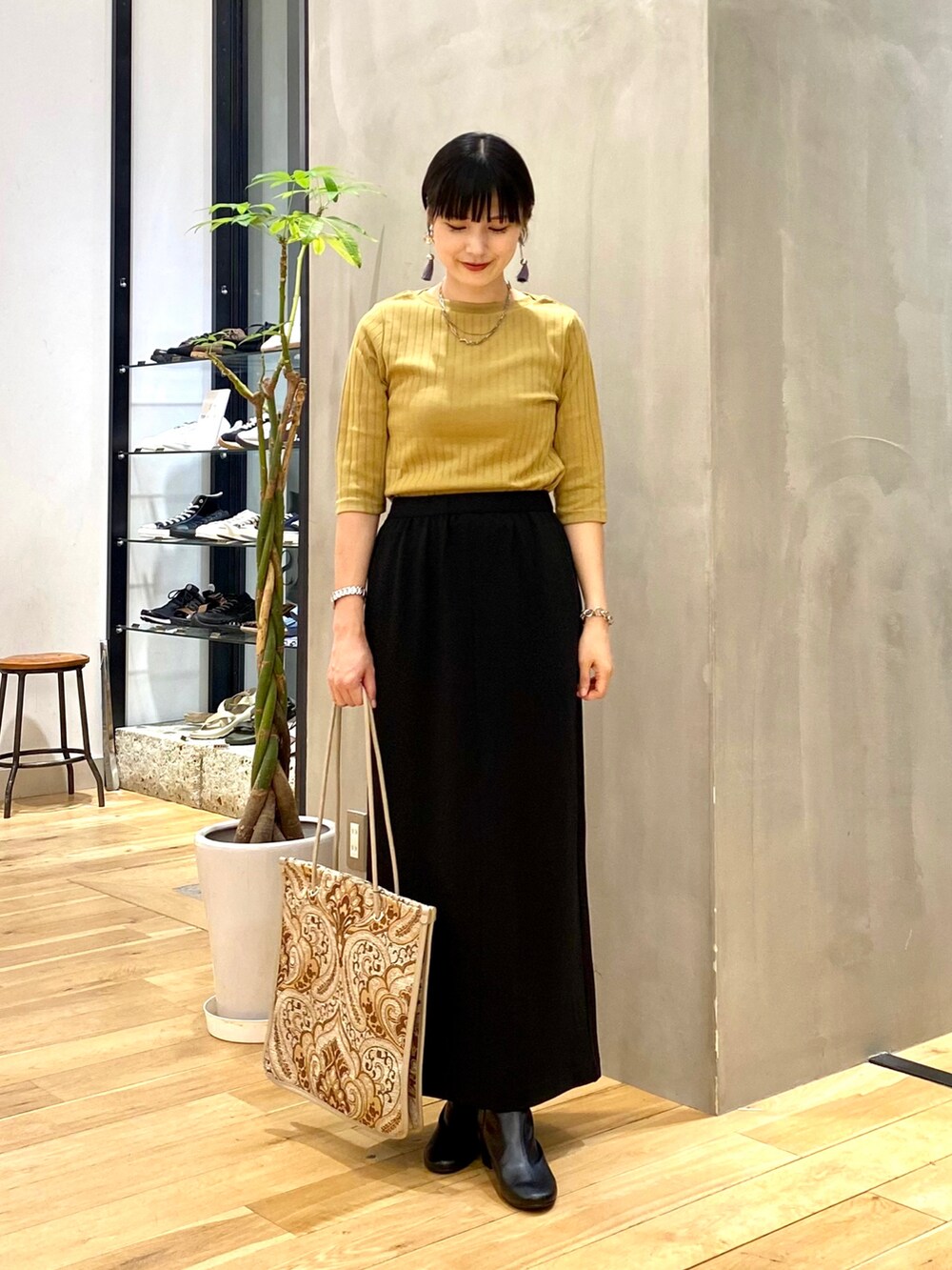 イエロー系のTシャツ/カットソー、ブラック系のスカート、ホワイト系のトートバッグを着用したレディースの秋コーディネートの2枚目の写真