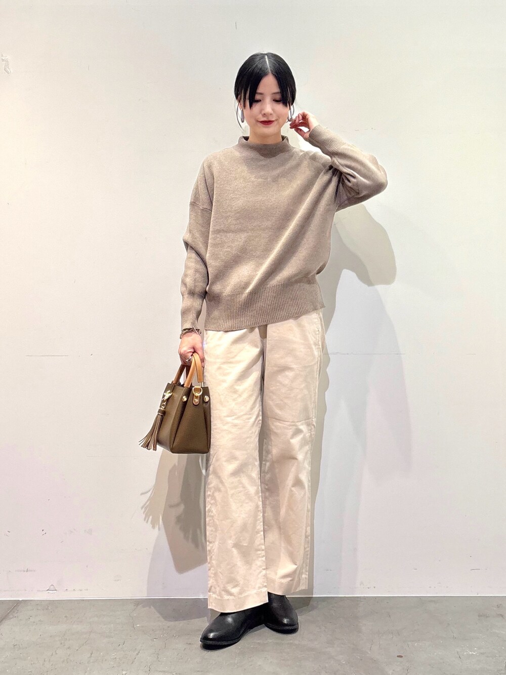 ブラック系のその他アウター、ベージュ系のニット/セーター、ホワイト系のその他パンツを着用したレディースの冬コーディネートの4枚目の写真