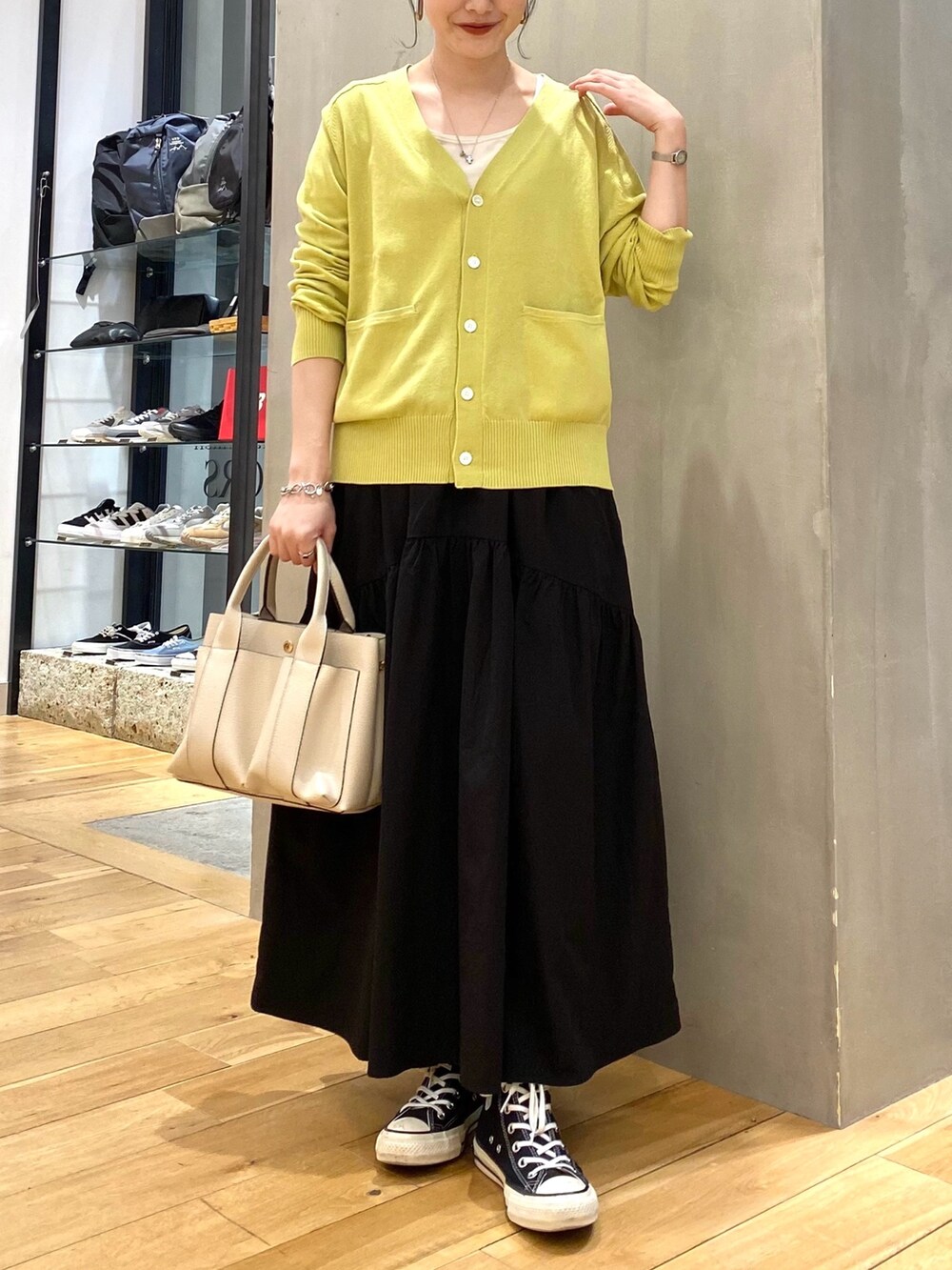 グリーン系のカーディガン/ボレロ、ブラック系のスカート、ホワイト系のトートバッグを着用したレディースの春コーディネートの3枚目の写真