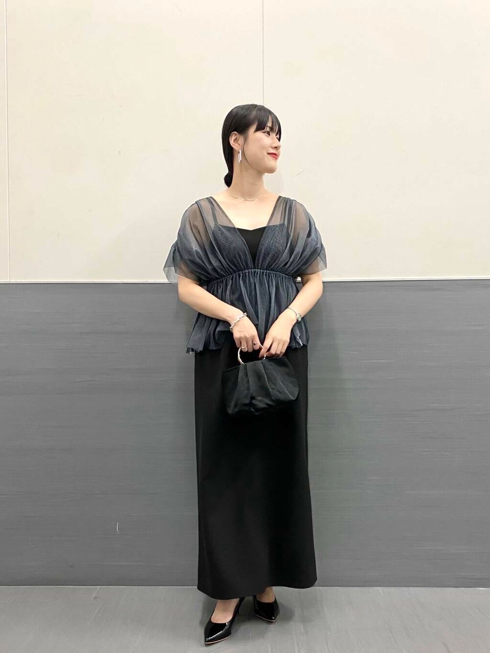 ブラック系のパンプス、ブラック系のハンドバッグ、ブラック系のワンピースを着用したレディースの秋コーディネートの3枚目の写真