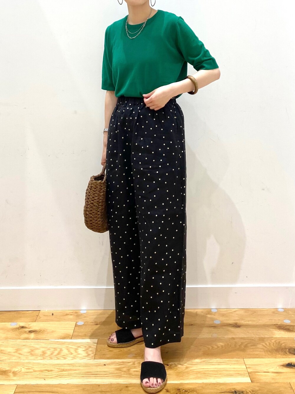 グリーン系のニット/セーター、ブラック系のその他パンツ、ブラウン系のハンドバッグを着用したレディースの春コーディネートの4枚目の写真