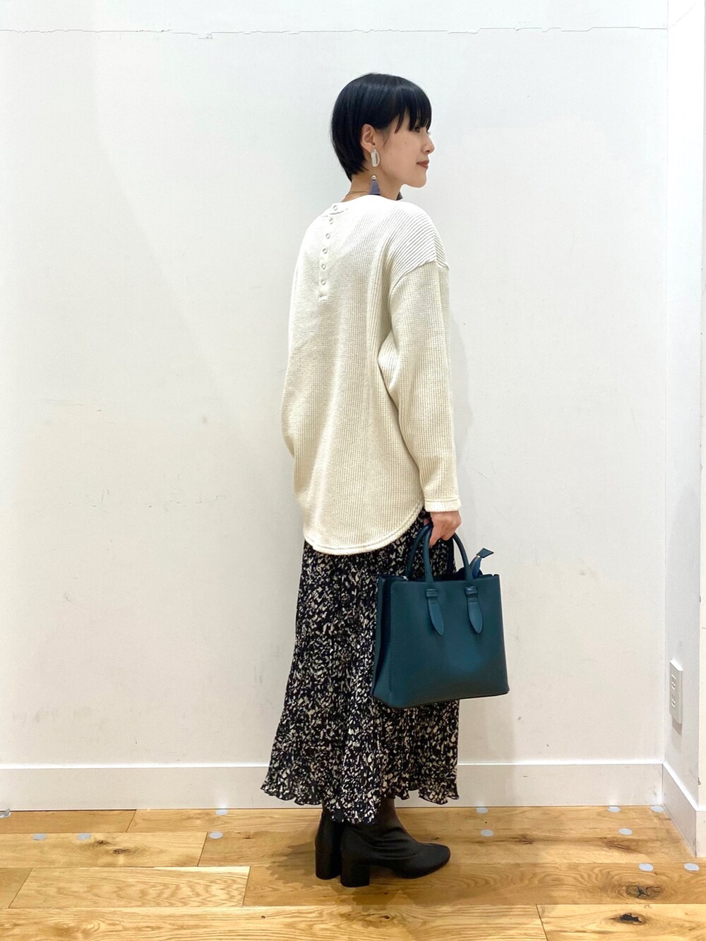 ブラウン系のステンカラーコート、ホワイト系のTシャツ/カットソー、ブラック系のスカートを着用したレディースの冬コーディネートの5枚目の写真