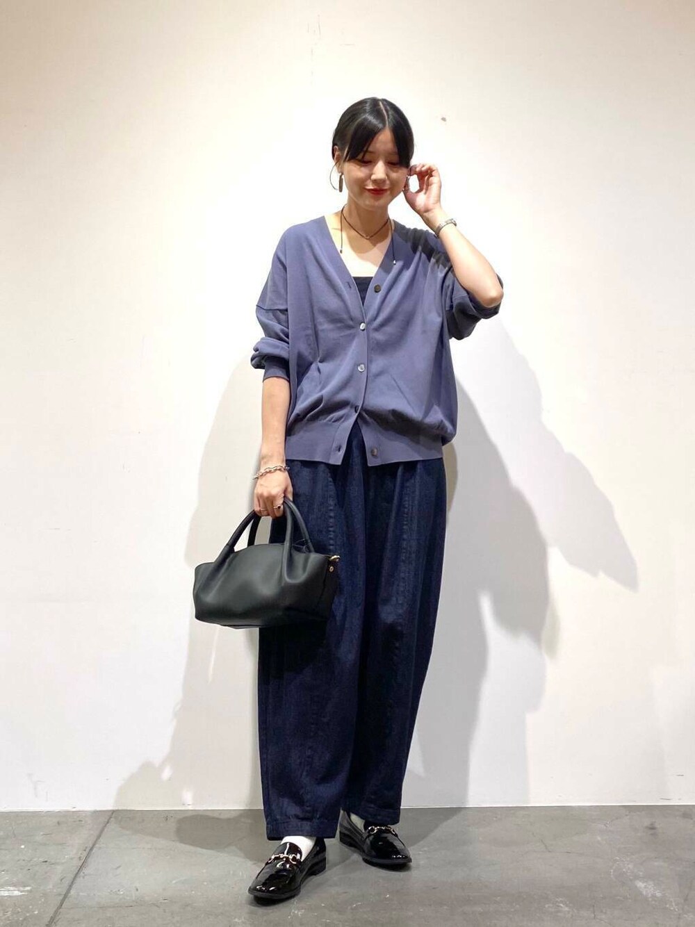 ブラック系のローファー、ブルー系のデニムパンツ、ブルー系のカーディガン/ボレロを着用したレディースの秋コーディネートの3枚目の写真