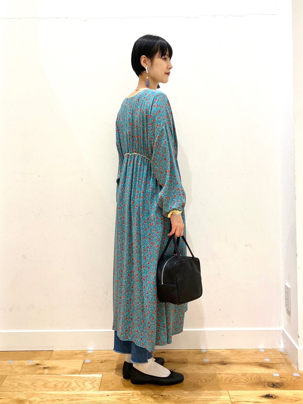 ホワイト系のチェスターコート、グリーン系のワンピース、ブルー系のデニムパンツを着用したレディースの冬コーディネートの4枚目の写真