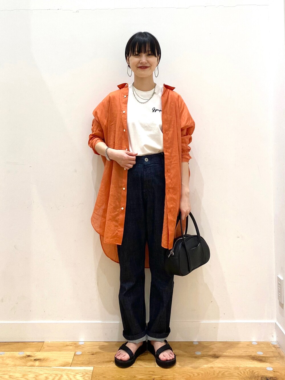 オレンジ系のシャツ/ブラウス、ホワイト系のTシャツ/カットソー、ブルー系のデニムパンツを着用したレディースの春コーディネートの2枚目の写真