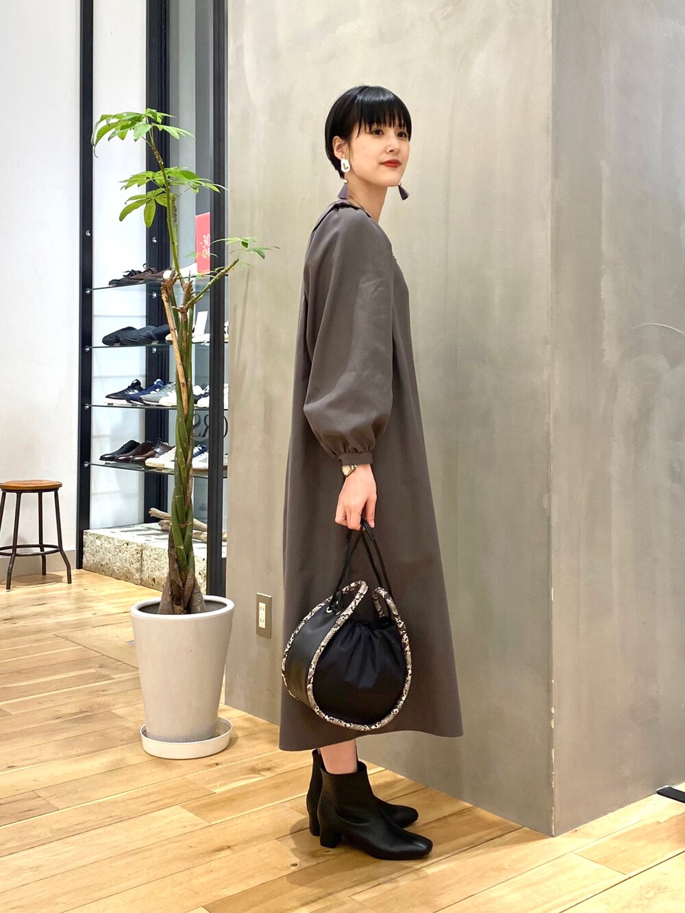 グレー系のワンピース、ブラック系のショルダーバッグ、ブラック系のブーツを着用したレディースの冬コーディネートの5枚目の写真