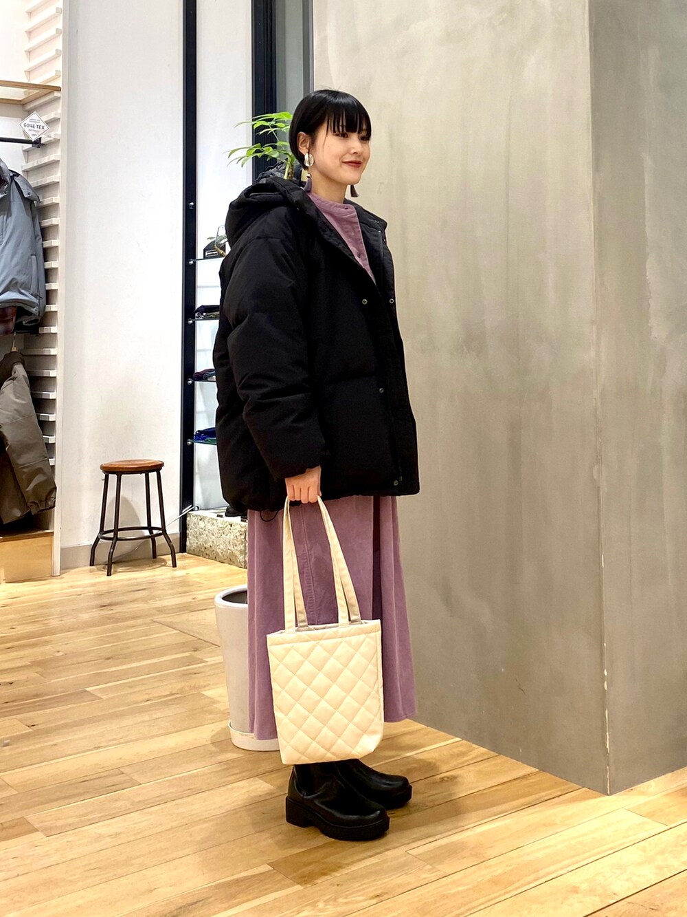 ブラック系のダウンジャケット/コート、パープル系のワンピース、ホワイト系のトートバッグを着用したレディースの冬コーディネートの2枚目の写真