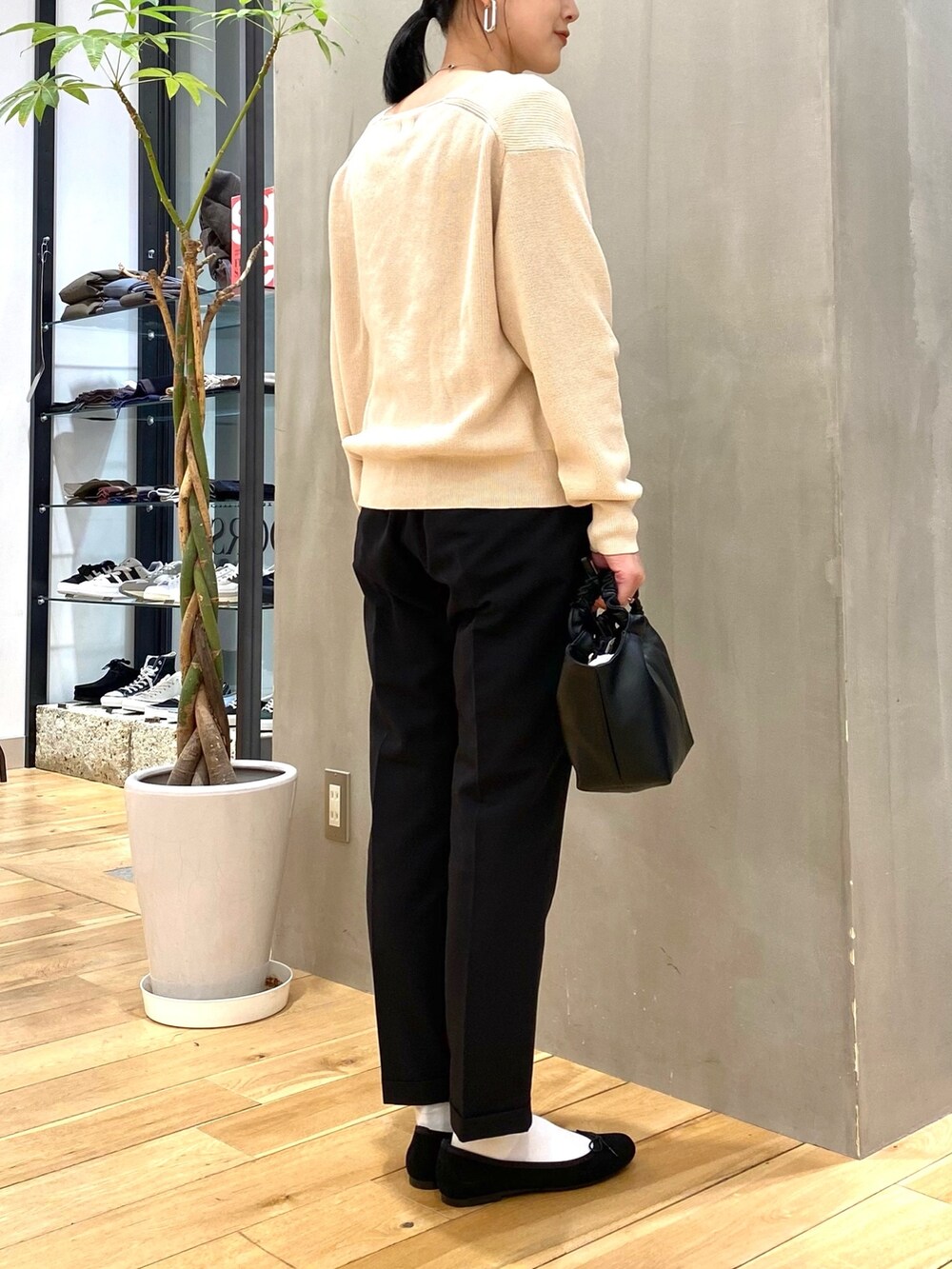 グリーン系のステンカラーコート、ホワイト系のニット/セーター、ブラック系のその他パンツを着用したレディースの冬コーディネートの8枚目の写真