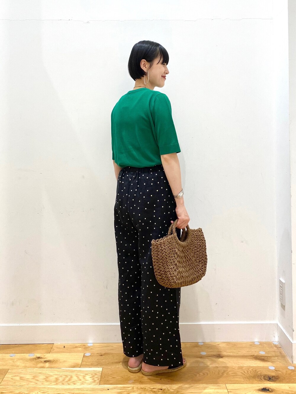 グリーン系のニット/セーター、ブラック系のその他パンツ、ブラウン系のハンドバッグを着用したレディースの春コーディネートの3枚目の写真