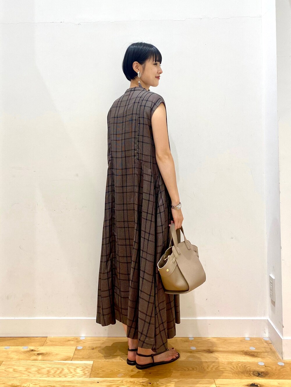 ブラウン系のワンピース、ブラウン系のハンドバッグ、ブラック系のサンダルを着用したレディースの夏コーディネートの3枚目の写真