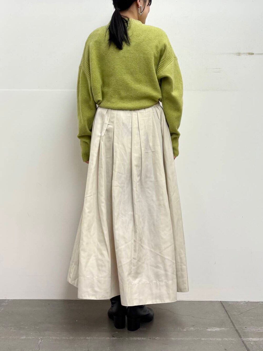 ブラック系のブーツ、ホワイト系のスカート、グリーン系のニット/セーターを着用したレディースの冬コーディネートの5枚目の写真