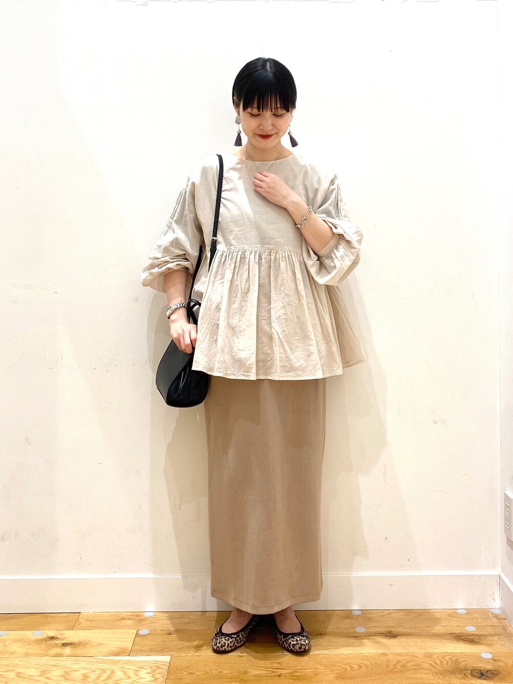 グレー系のシャツ/ブラウス、ベージュ系のスカート、ブラック系のショルダーバッグを着用したレディースの春コーディネートの2枚目の写真