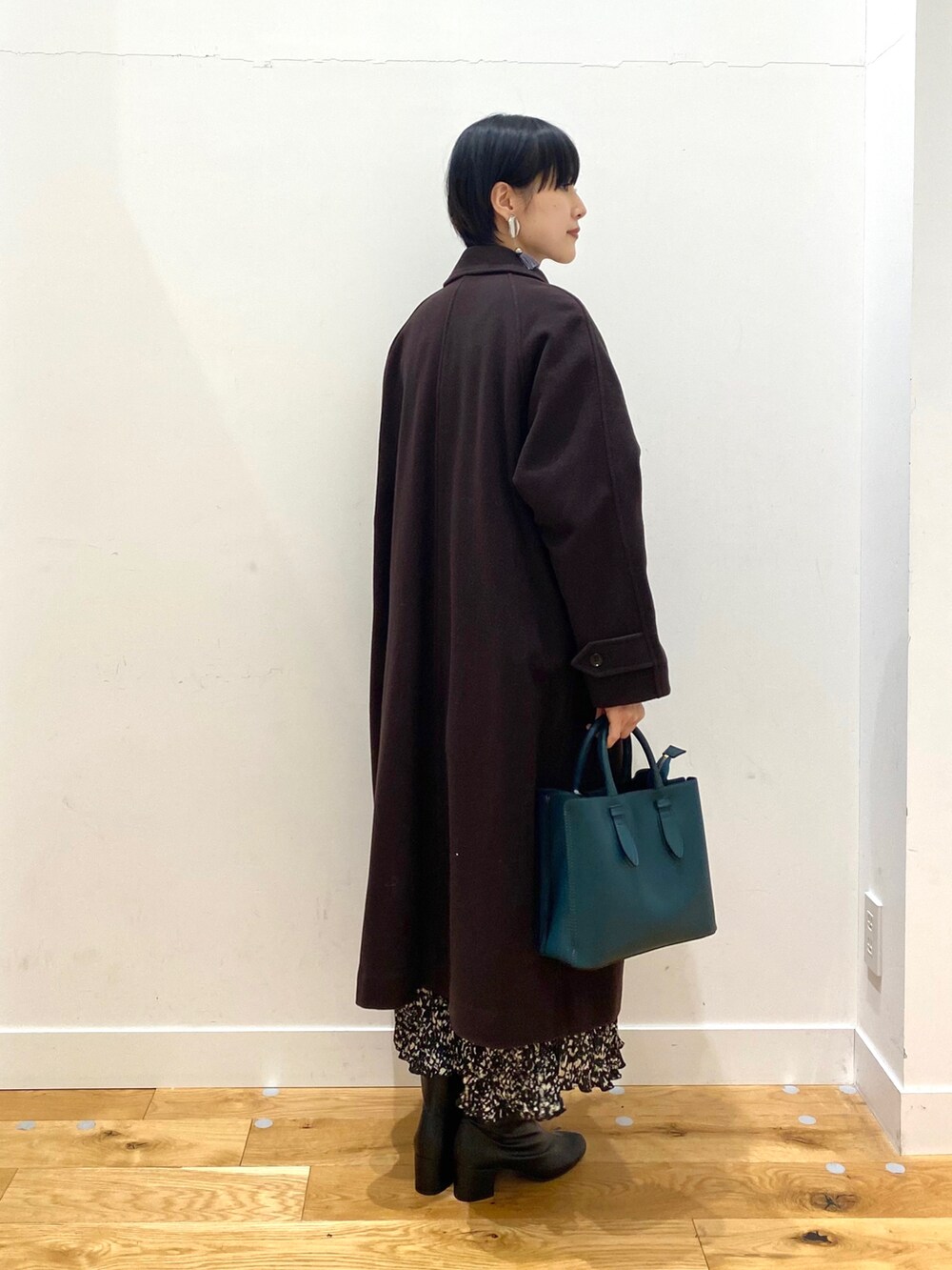 ブラウン系のステンカラーコート、ホワイト系のTシャツ/カットソー、ブラック系のスカートを着用したレディースの冬コーディネートの3枚目の写真