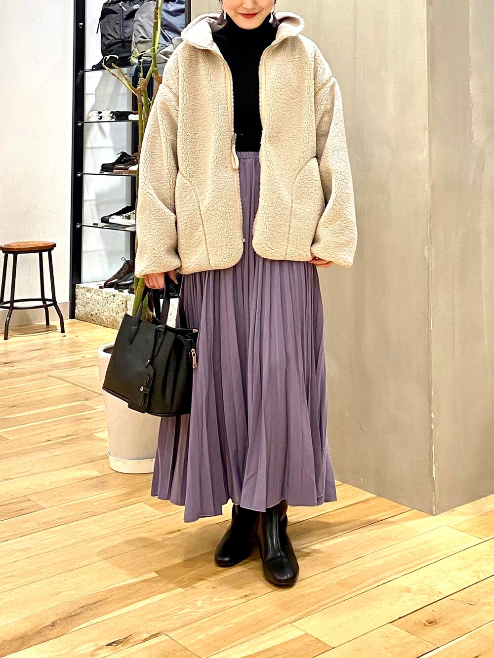ホワイト系のブルゾン、ブラック系のニット/セーター、パープル系のスカートを着用したレディースの冬コーディネートの4枚目の写真