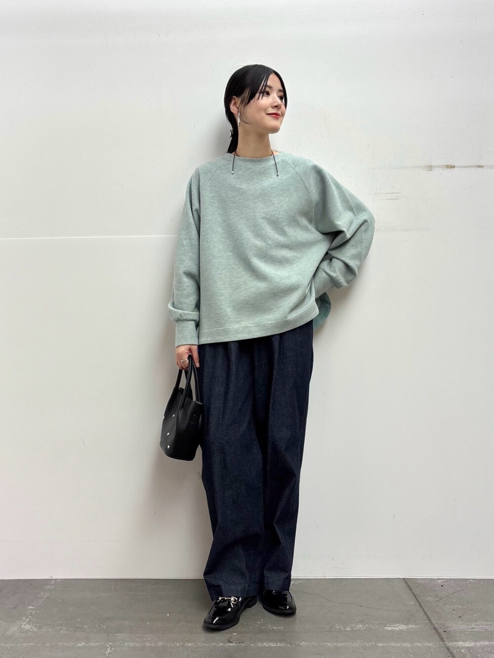 グリーン系のTシャツ/カットソー、ブルー系のデニムパンツ、ブラック系のショルダーバッグを着用したレディースの冬コーディネートの2枚目の写真