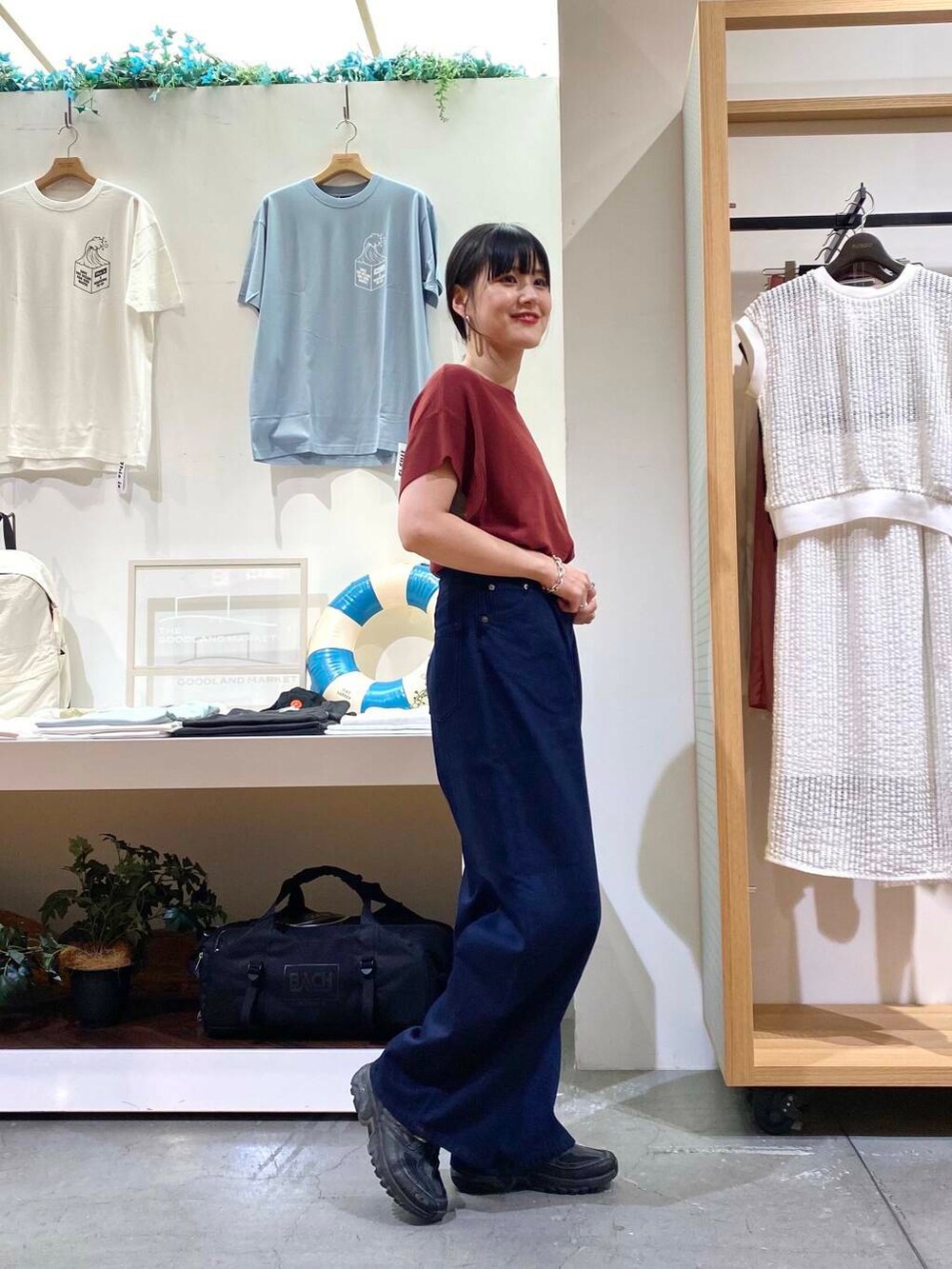 レッド系のニット/セーター、ブルー系のデニムパンツを着用したレディースの夏コーディネートの3枚目の写真