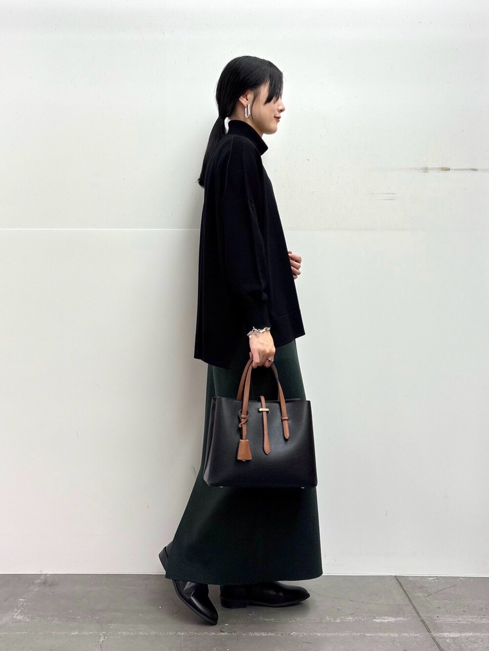 ブラック系のその他アウター、ブラック系のニット/セーター、グリーン系のスカートを着用したレディースの冬コーディネートの5枚目の写真