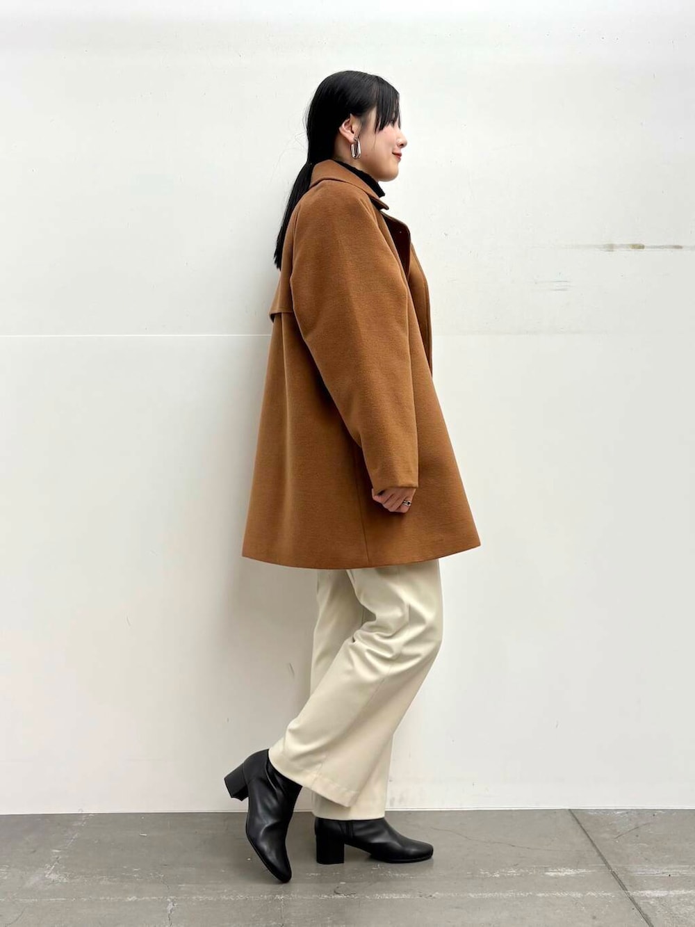 ブラック系のブーツ、イエロー系のステンカラーコート、ホワイト系のその他パンツを着用したレディースの冬コーディネートの2枚目の写真