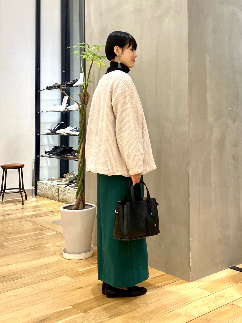 ホワイト系のノーカラージャケット、ブラック系のTシャツ/カットソー、グリーン系のスカートを着用したレディースの秋コーディネートの2枚目の写真