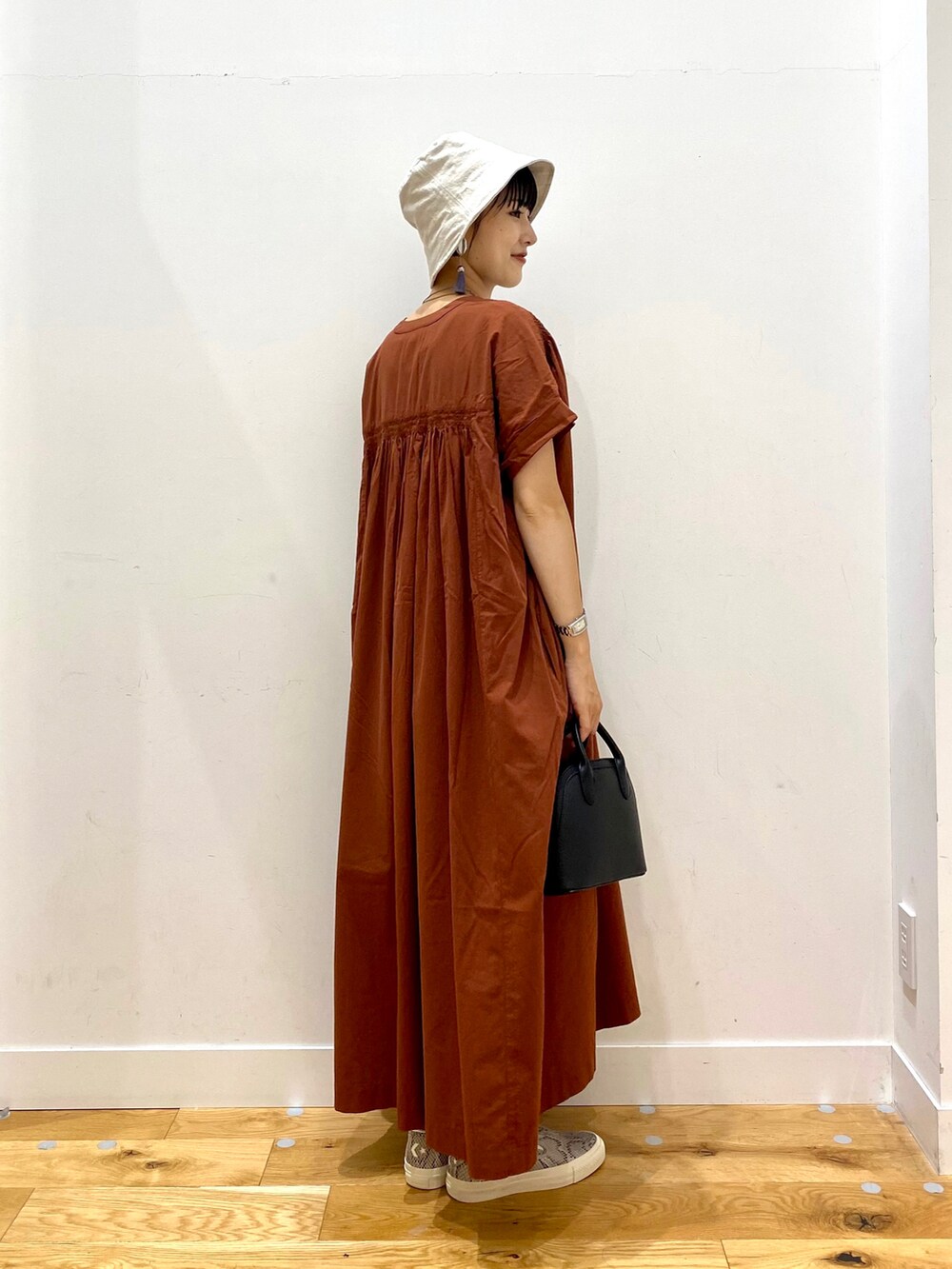 レッド系のワンピース、ブラック系のショルダーバッグ、ベージュ系のハットを着用したレディースの夏コーディネートの3枚目の写真