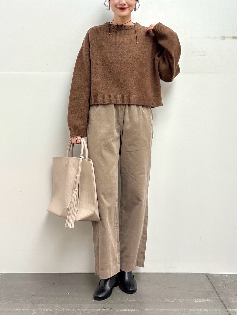 ブラウン系のニット/セーター、ベージュ系のその他パンツ、ホワイト系のトートバッグを着用したレディースの冬コーディネートの4枚目の写真