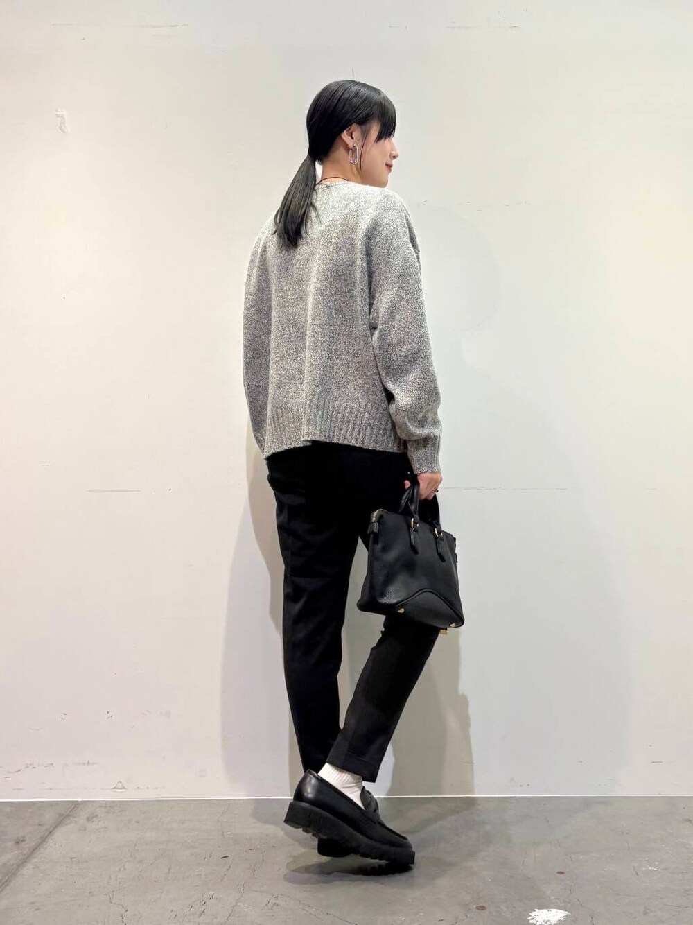 グレー系のニット/セーター、ブラック系のボストンバッグ、グレー系のその他パンツを着用したレディースの冬コーディネートの3枚目の写真
