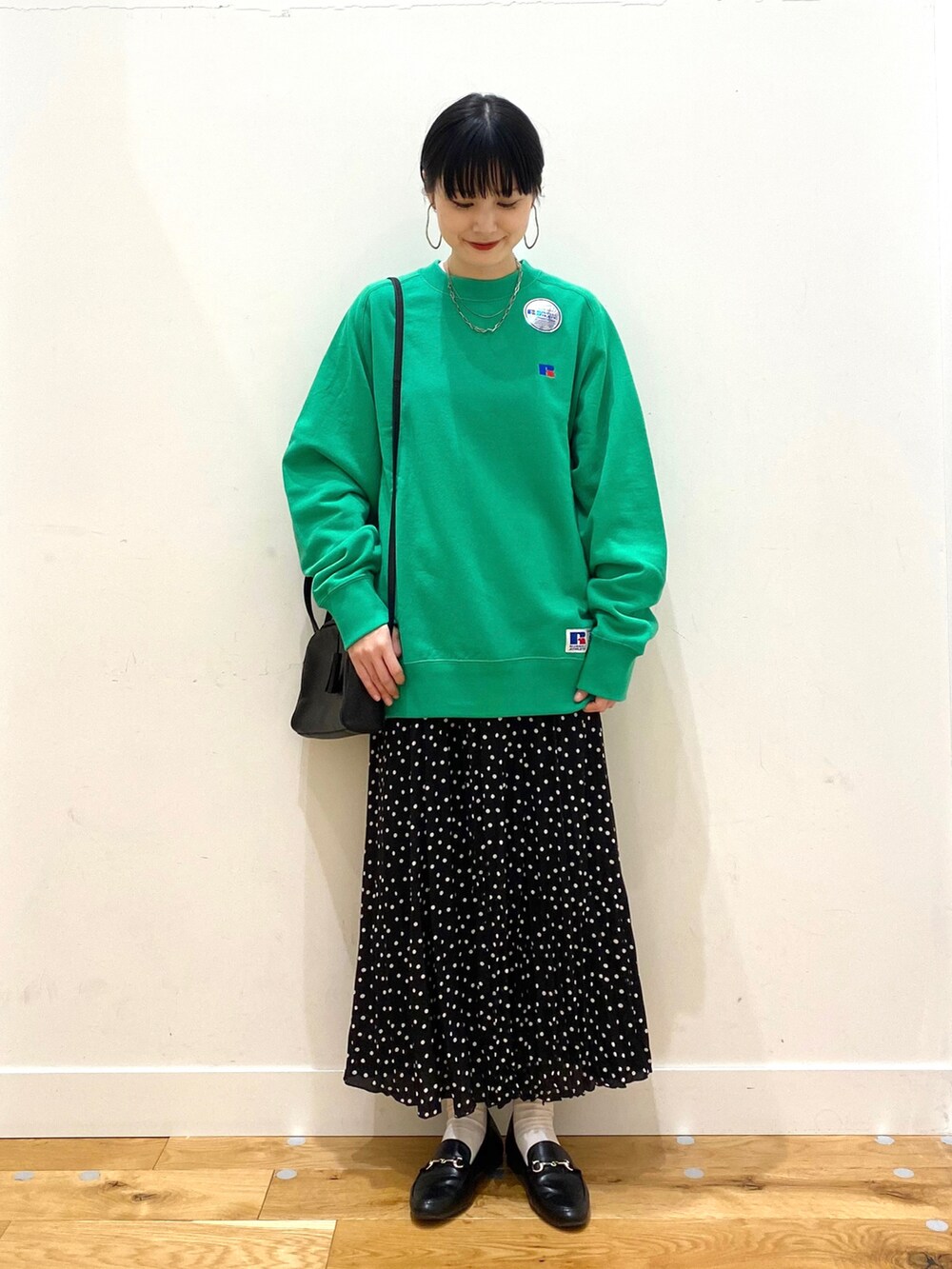 グリーン系のスウェット、ブラック系のスカート、ブラック系のボストンバッグを着用したレディースの冬コーディネートの2枚目の写真