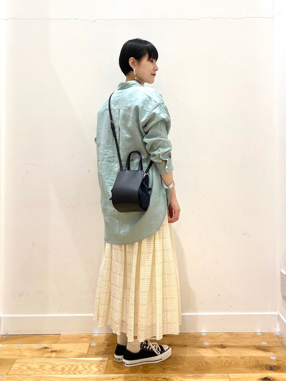 グリーン系のシャツ/ブラウス、ホワイト系のスカート、ブラック系のショルダーバッグを着用したレディースの春コーディネートの3枚目の写真