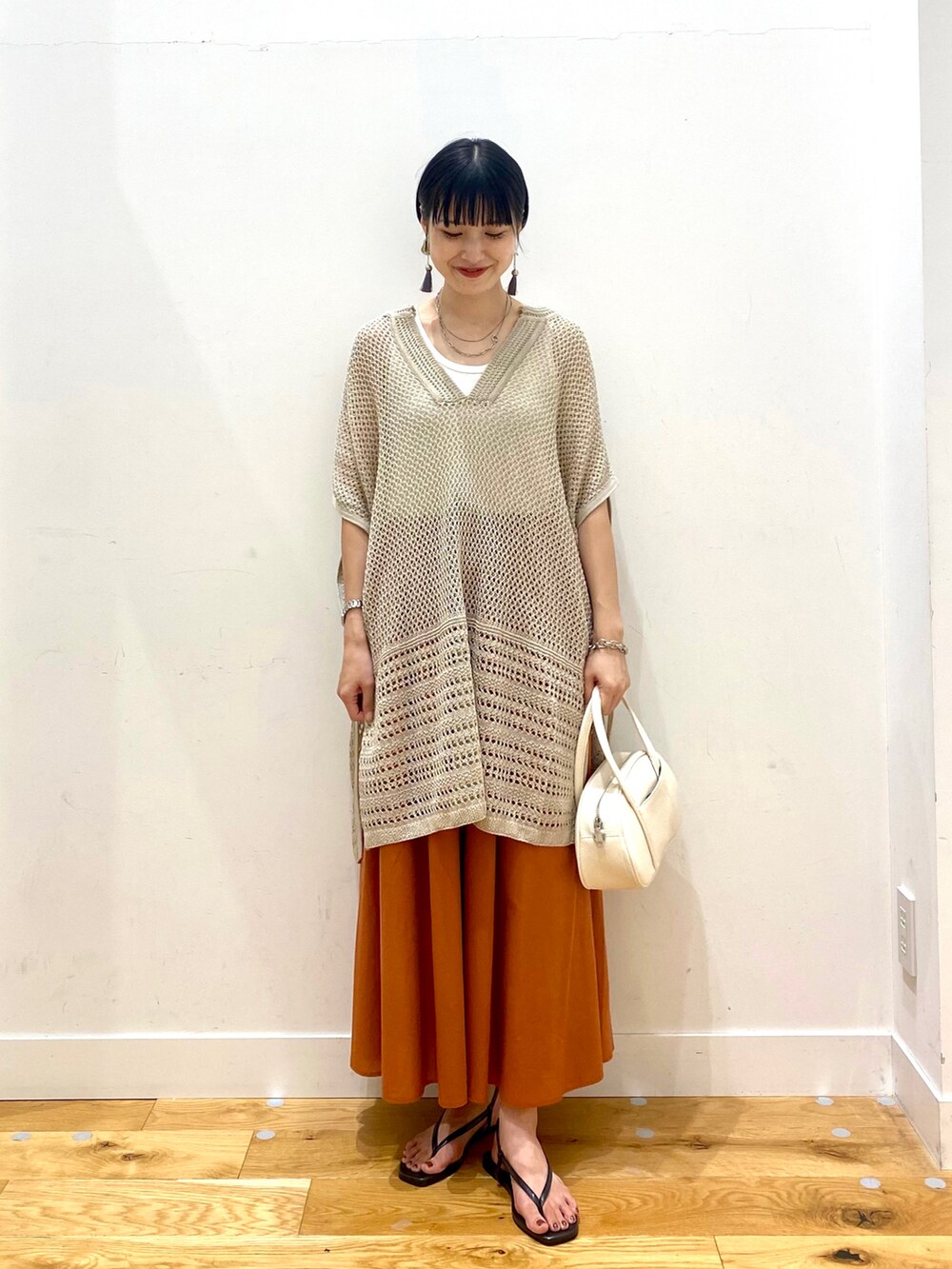 ベージュ系のニット/セーター、ホワイト系のタンクトップ、オレンジ系のスカートを着用したレディースの夏コーディネートの2枚目の写真