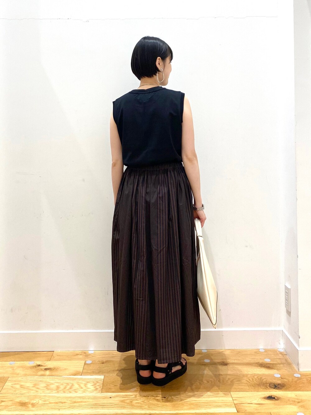 ブラック系のTシャツ/カットソー、ブラウン系のスカート、ホワイト系のトートバッグを着用したレディースの春コーディネートの3枚目の写真