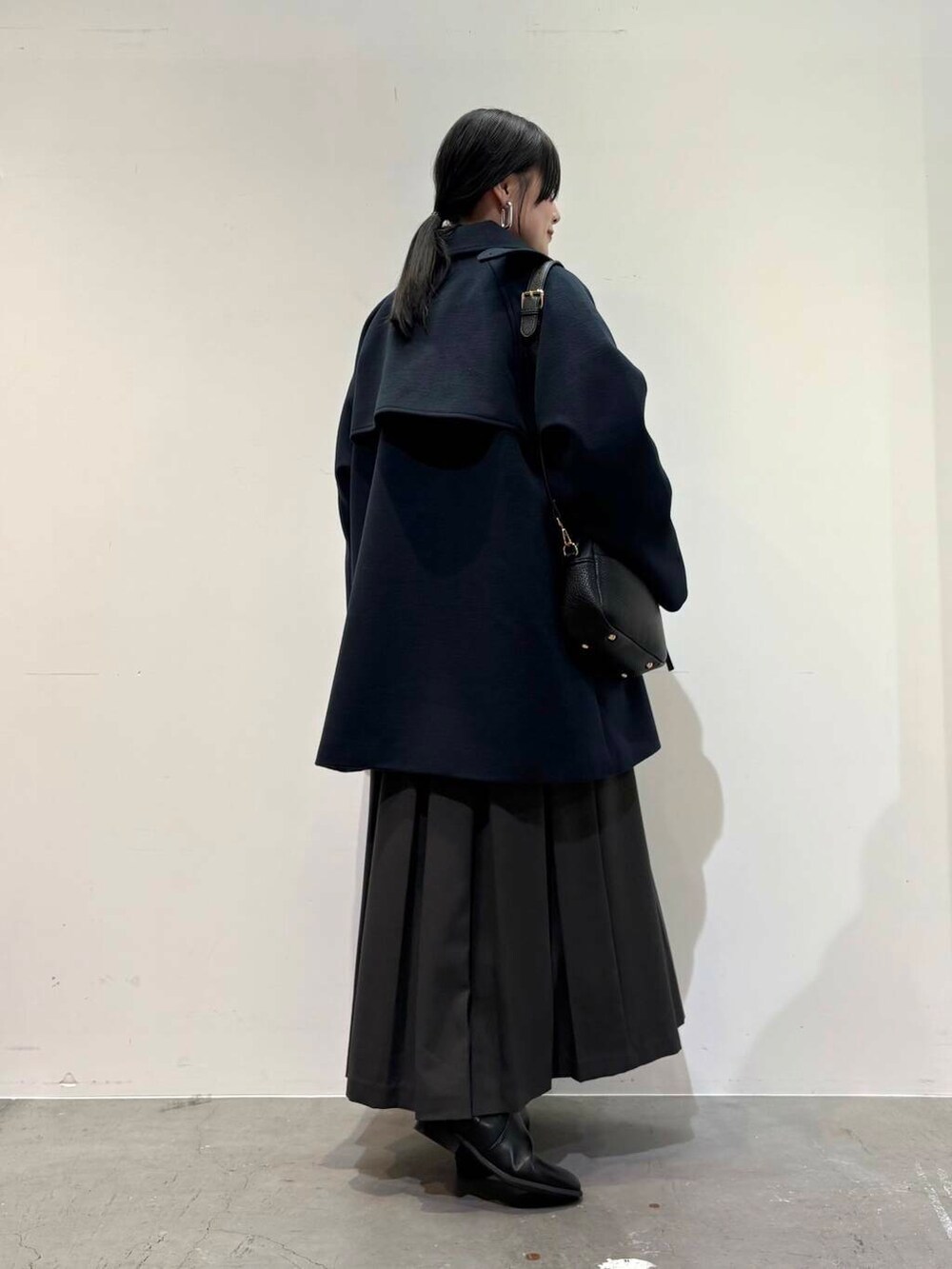 ブラック系のショルダーバッグ、グレー系のスカート、ブラック系のブーツを着用したレディースの冬コーディネートの3枚目の写真