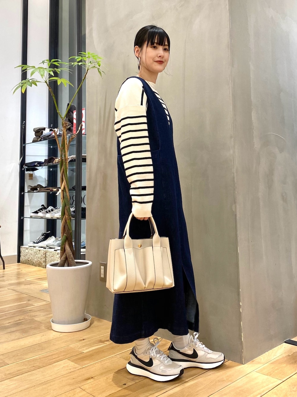 ホワイト系のニット/セーター、ブルー系のジャンパースカート、ホワイト系のトートバッグを着用したレディースの冬コーディネートの2枚目の写真