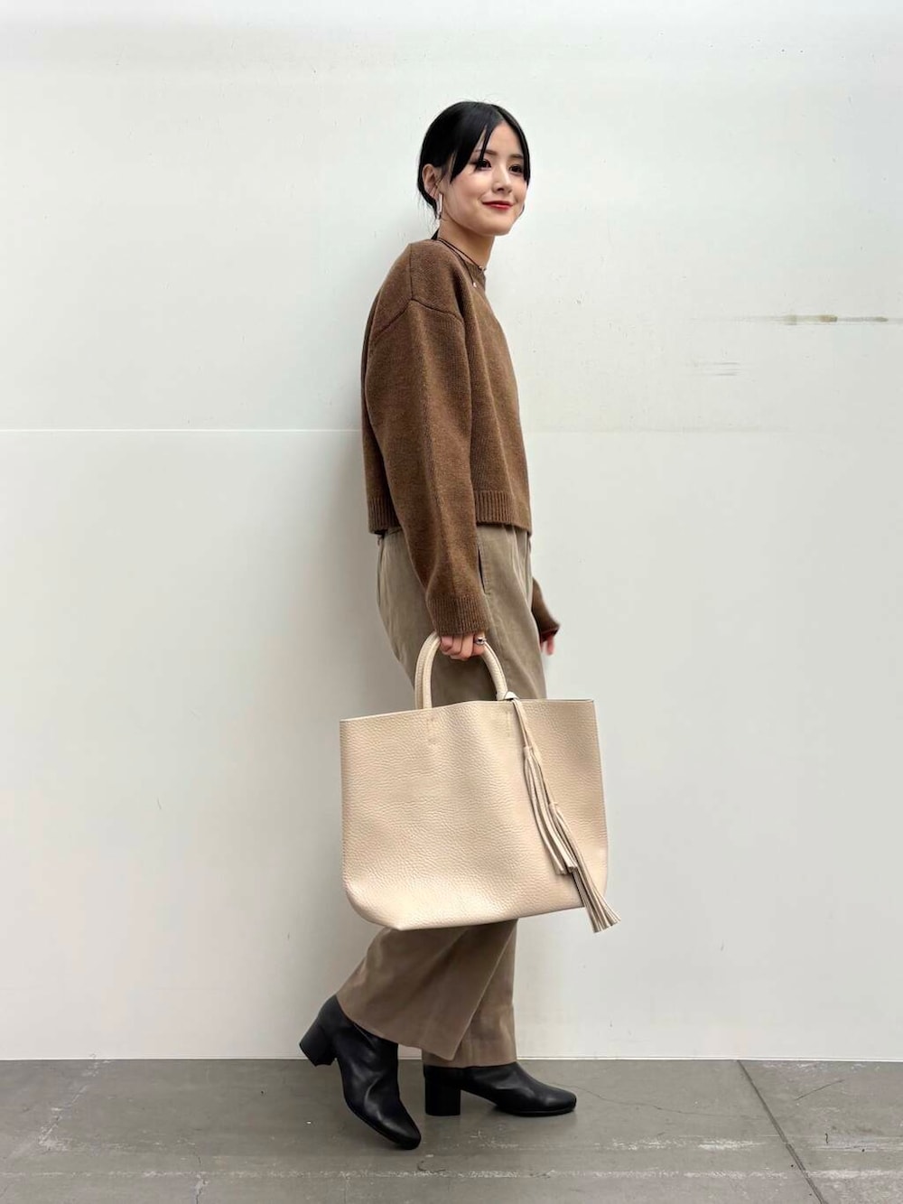 ブラック系のブーツ、ホワイト系のトートバッグ、ベージュ系のその他パンツを着用したレディースの冬コーディネートの2枚目の写真