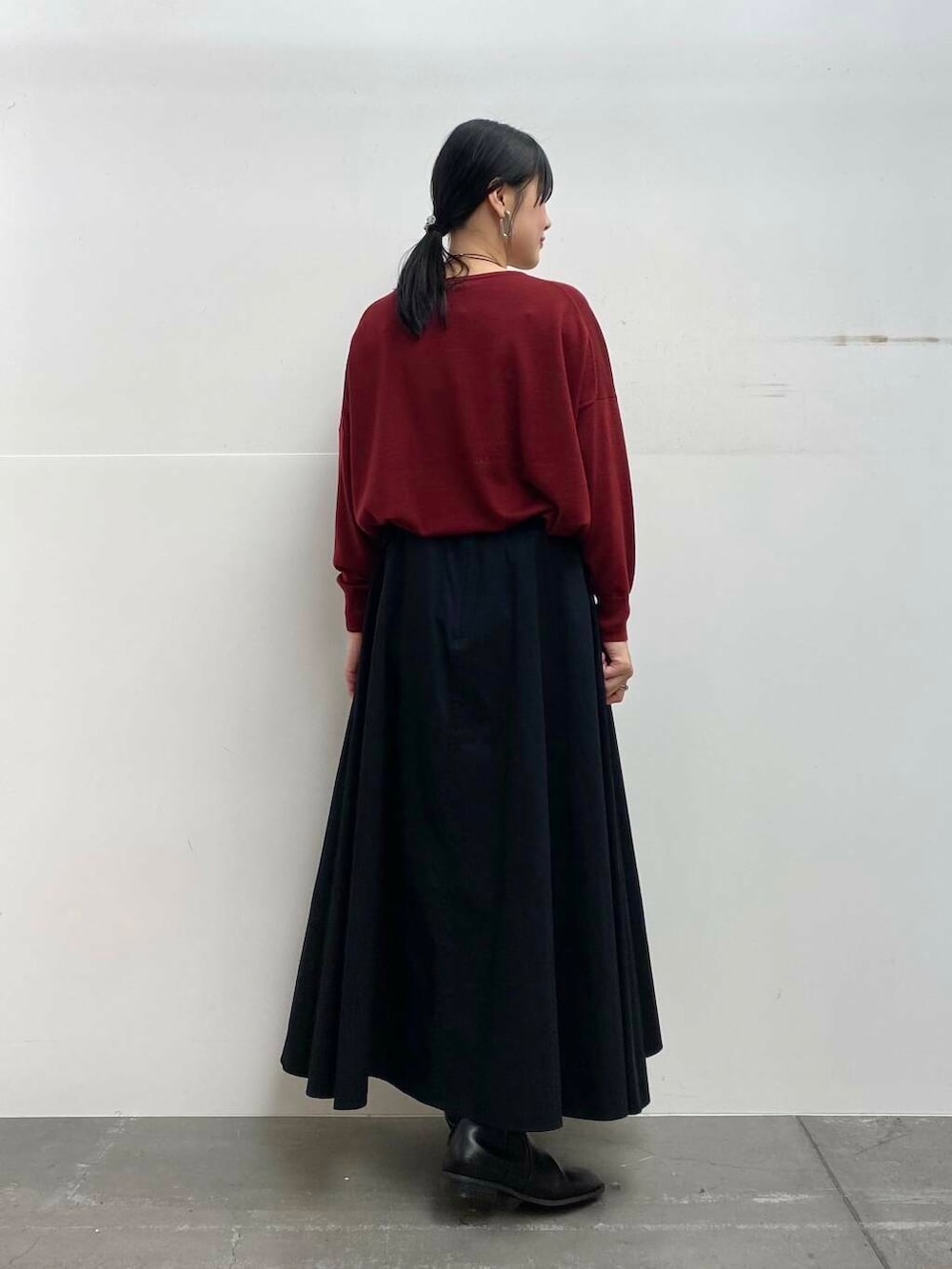 レッド系のニット/セーター、ブラック系のブーツ、ブラック系のスカートを着用したレディースの秋コーディネートの6枚目の写真