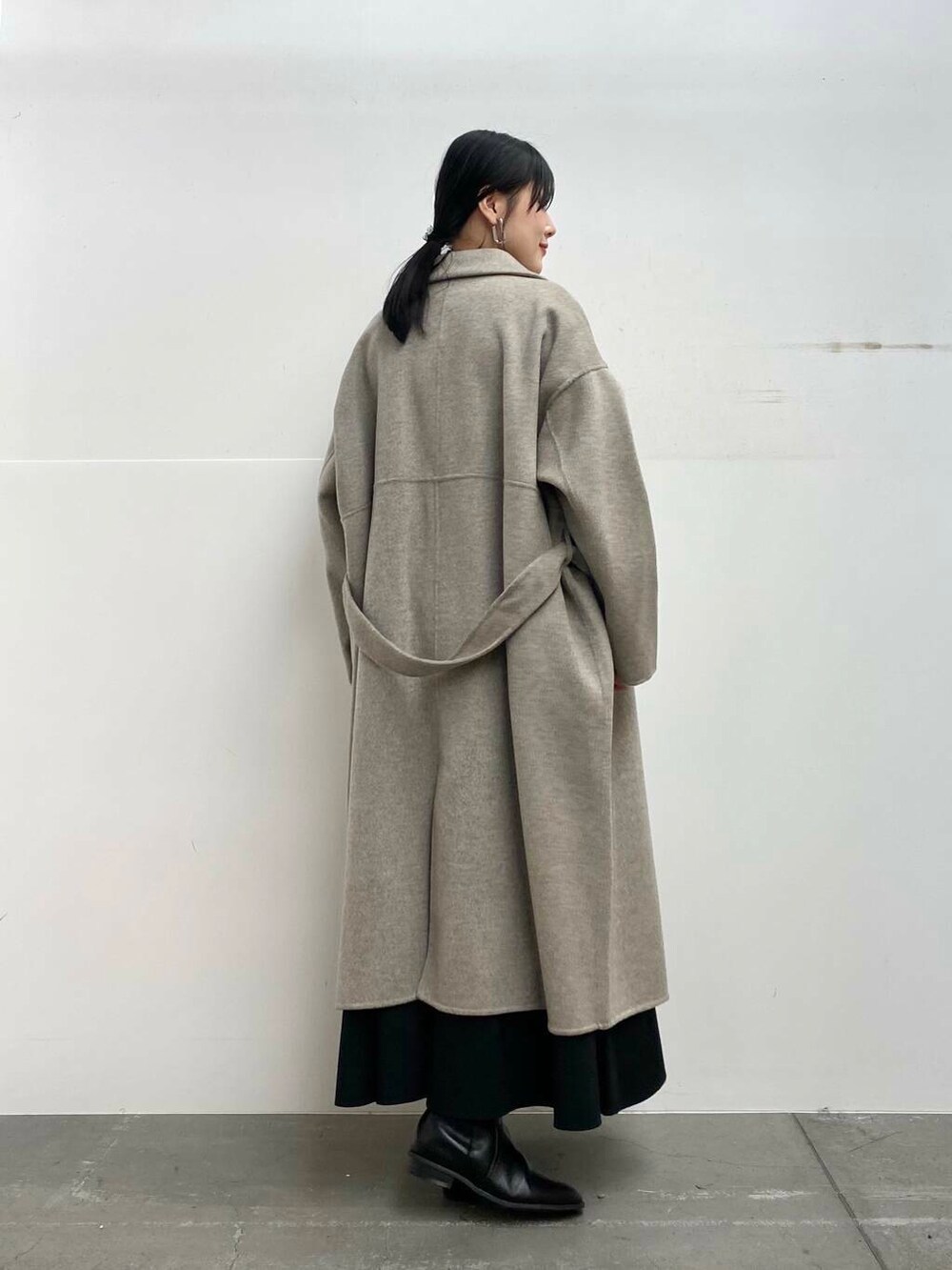 レッド系のニット/セーター、ブラック系のブーツ、ブラック系のスカートを着用したレディースの秋コーディネートの3枚目の写真