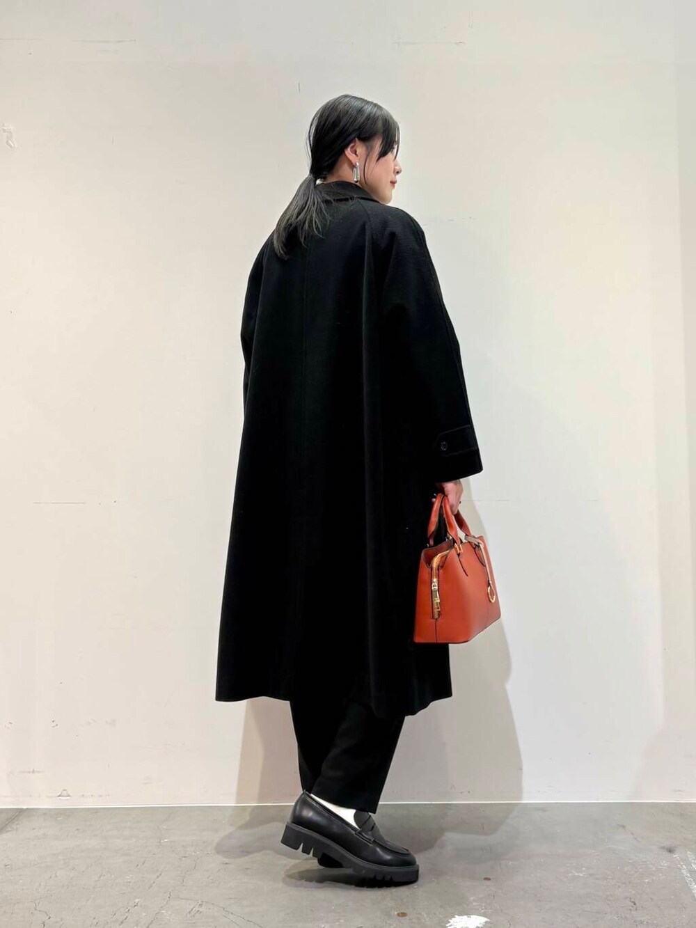 ブラック系のその他アウター、ホワイト系のシャツ/ブラウス、オレンジ系のハンドバッグを着用したレディースの冬コーディネートの3枚目の写真