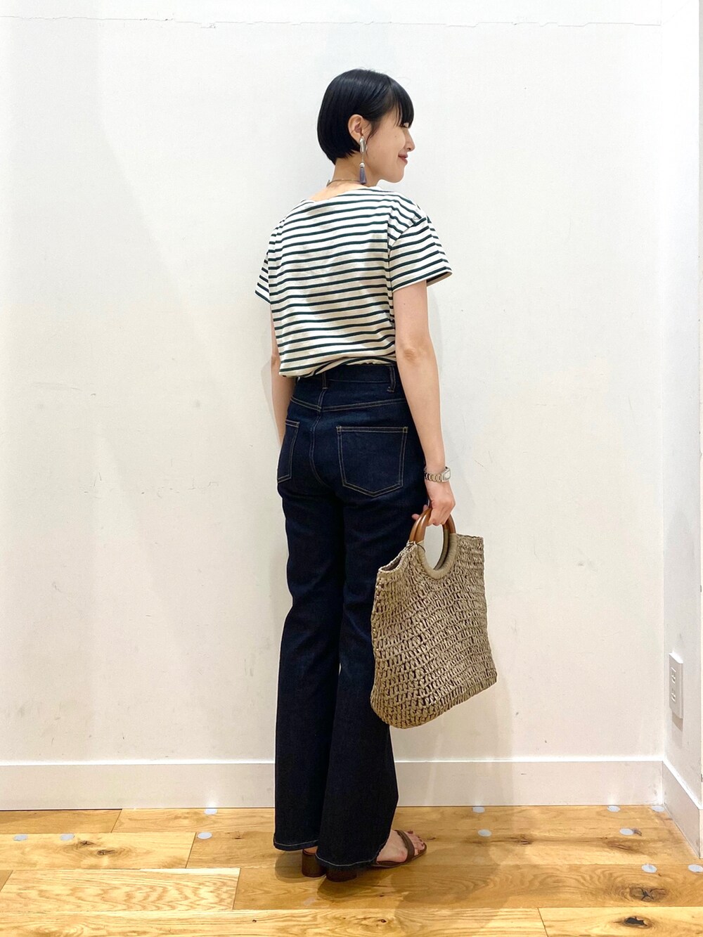 グリーン系のTシャツ/カットソー、ブルー系のデニムパンツ、グレー系のトートバッグを着用したレディースの春コーディネートの3枚目の写真