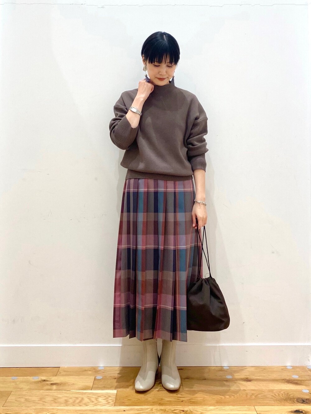ブルー系のチェスターコート、ブラウン系のニット/セーター、パープル系のスカートを着用したレディースの秋コーディネートの4枚目の写真