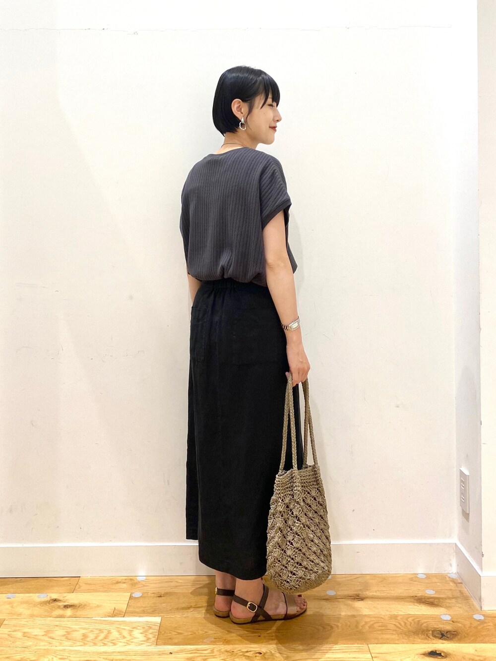 グレー系のTシャツ/カットソー、ブラック系のスカート、グレー系のトートバッグを着用したレディースの夏コーディネートの3枚目の写真