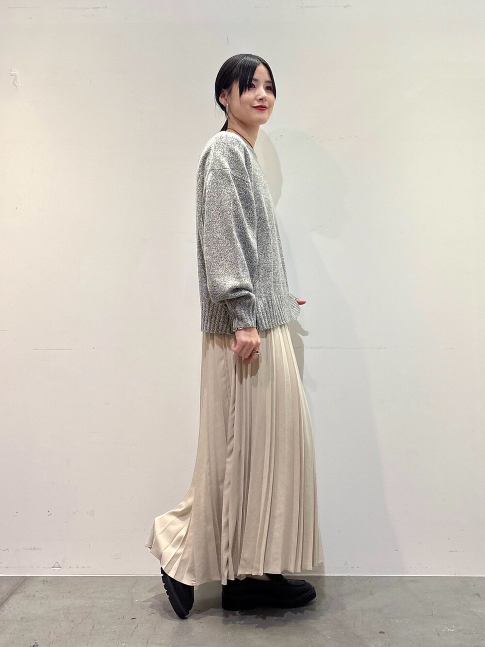 グレー系のニット/セーター、ホワイト系のスカート、ブラック系のローファーを着用したレディースの冬コーディネートの2枚目の写真