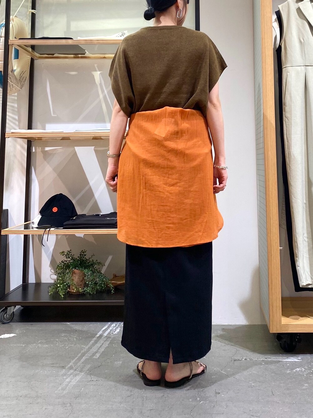 ブラウン系のニット/セーター、オレンジ系のシャツ/ブラウス、ブラック系のスカートを着用したレディースの夏コーディネートの8枚目の写真