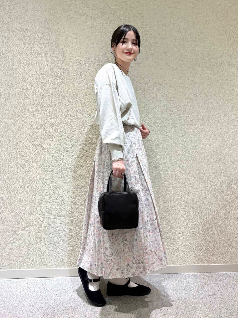 ベージュ系のTシャツ/カットソー、ホワイト系のスカート、ホワイト系のダウンジャケット/コートを着用したレディースの春コーディネートの5枚目の写真