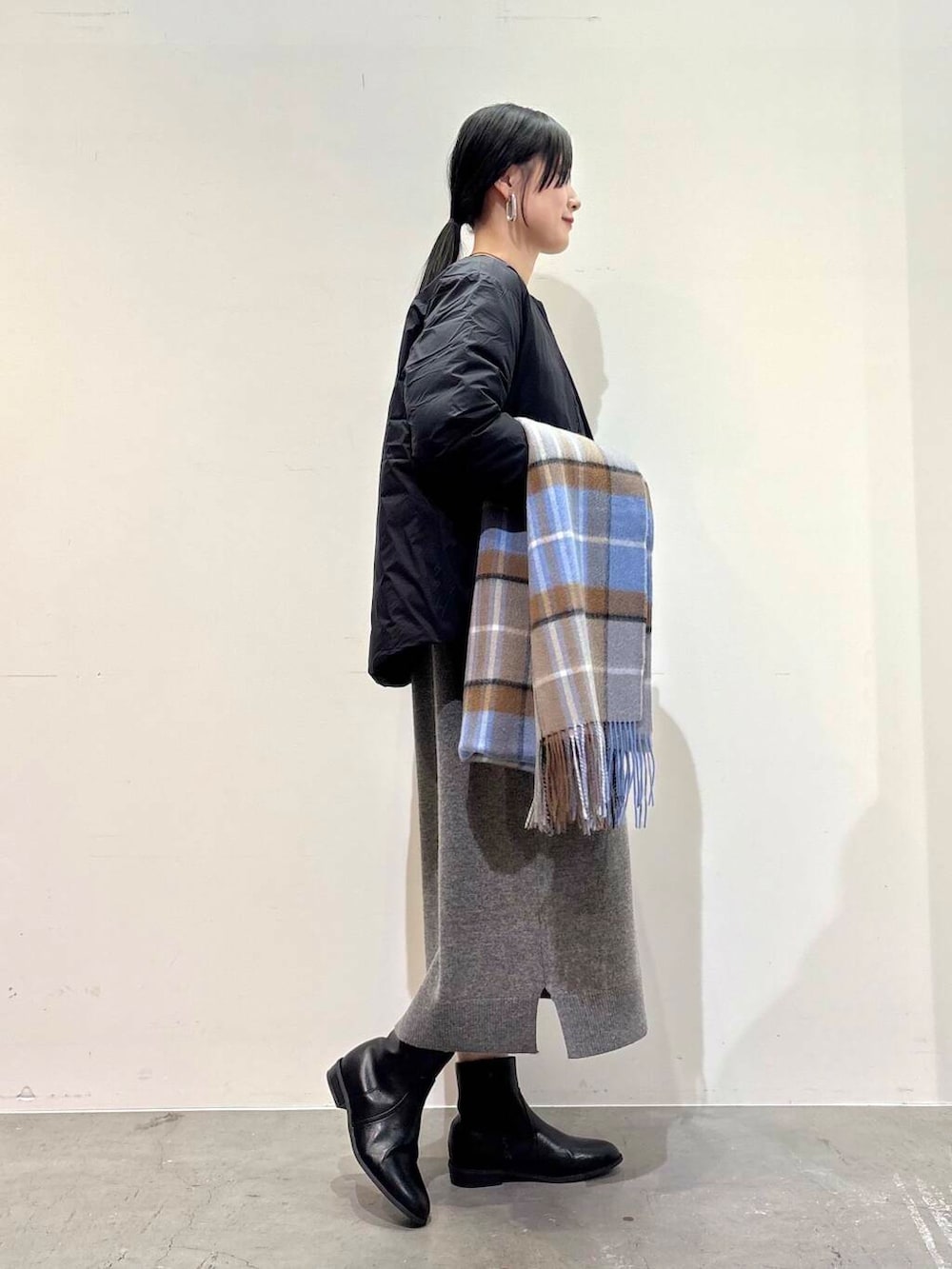 ブラック系のダウンジャケット/コート、ブラック系のブーツ、グレー系のワンピースを着用したレディースの冬コーディネートの2枚目の写真