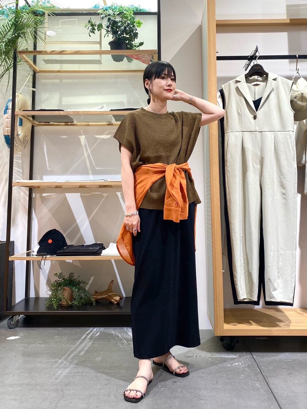 ブラウン系のニット/セーター、オレンジ系のシャツ/ブラウス、ブラック系のスカートを着用したレディースの夏コーディネートの2枚目の写真