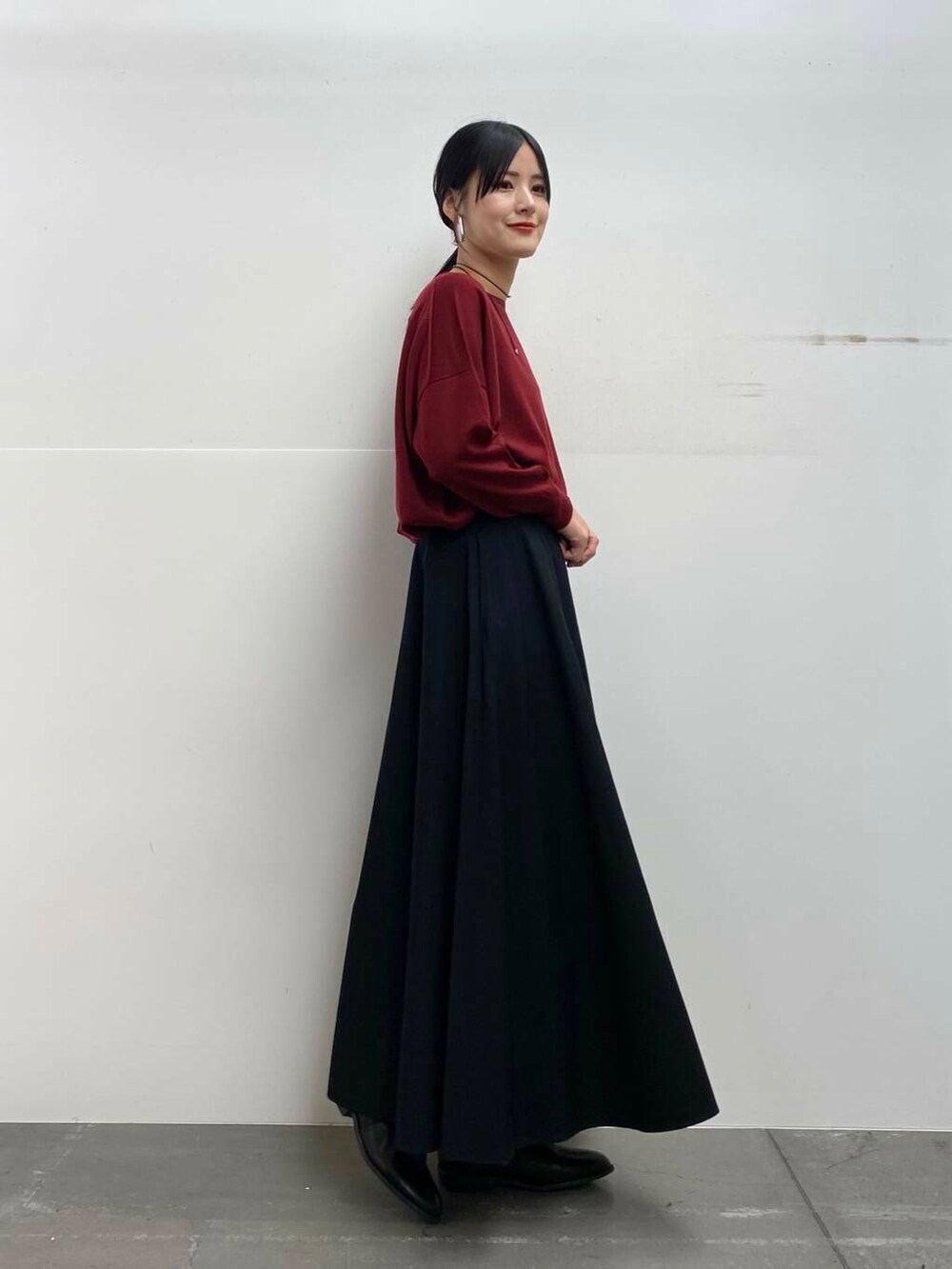 レッド系のニット/セーター、ブラック系のブーツ、ブラック系のスカートを着用したレディースの秋コーディネートの5枚目の写真