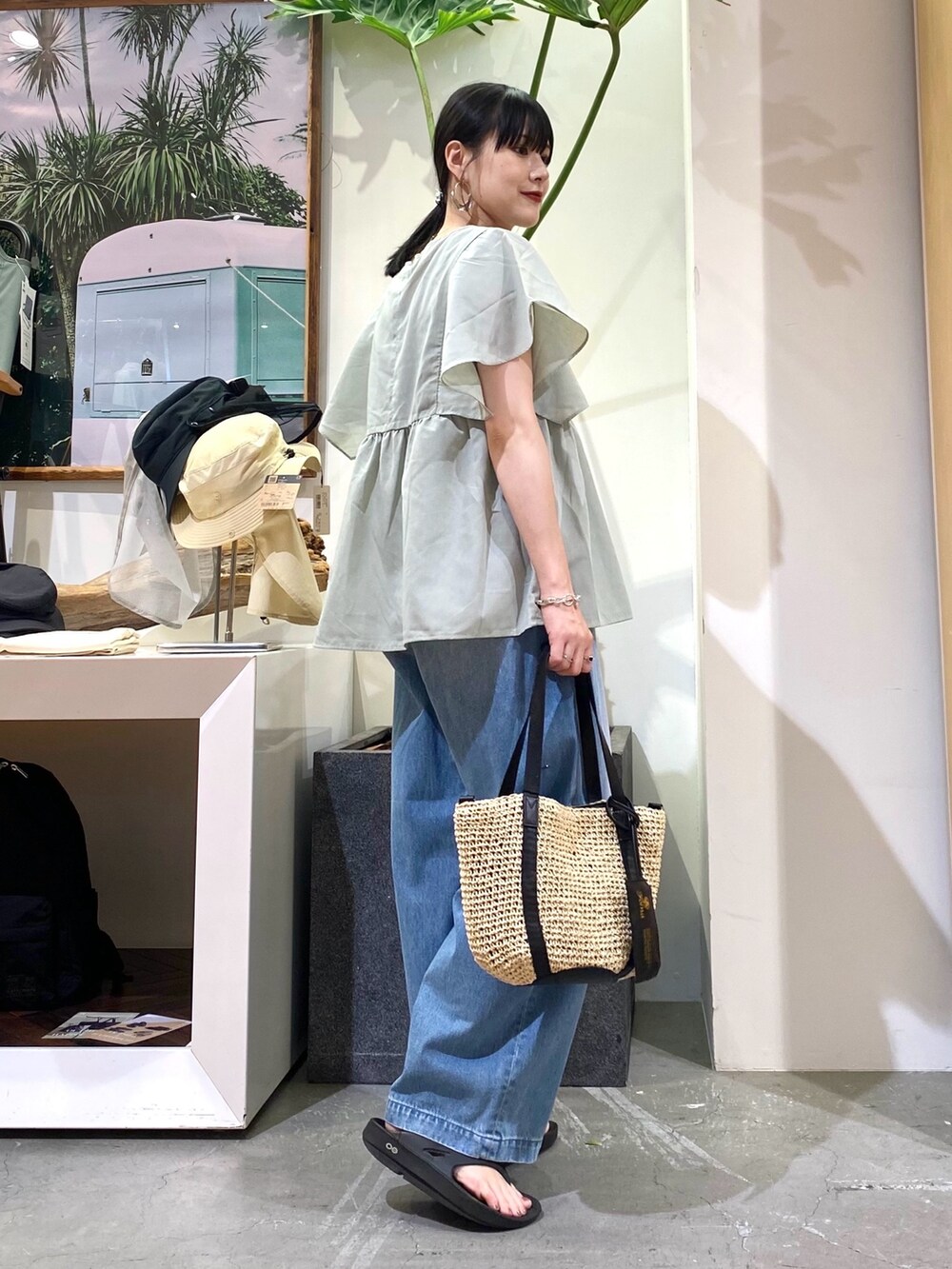 グリーン系のシャツ/ブラウス、ブルー系のデニムパンツ、ベージュ系のトートバッグを着用したレディースの夏コーディネートの3枚目の写真