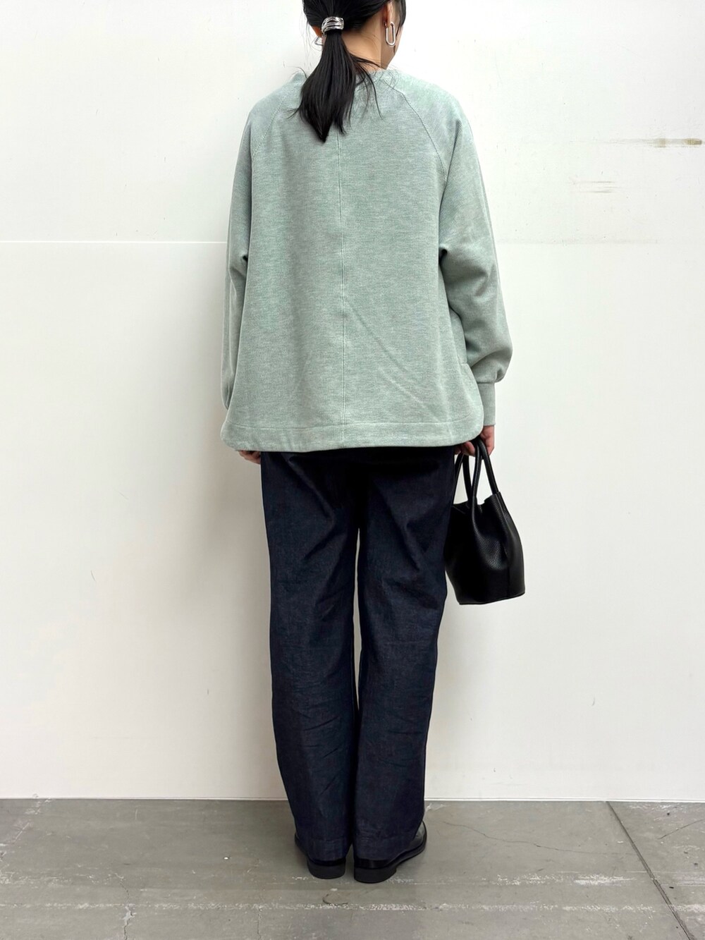 グリーン系のTシャツ/カットソー、ブルー系のデニムパンツ、ブラック系のショルダーバッグを着用したレディースの冬コーディネートの6枚目の写真